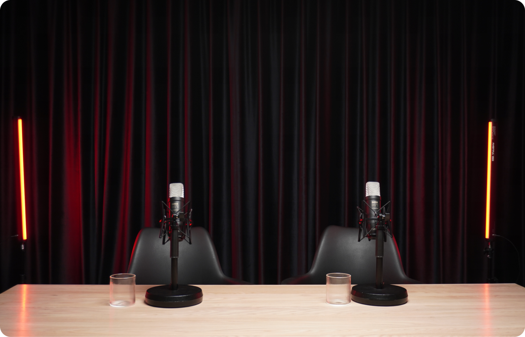 Студия записи подкастов Говорящая Голова в Севастополе: два микрофона Rode NT1 на столе, чёрные стулья, красные LED-трубки
